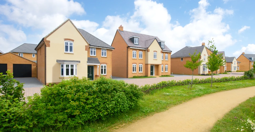Exterior view of modern brick residential homes featuring large windows, manicured lawns, and driveways under a clear sky.