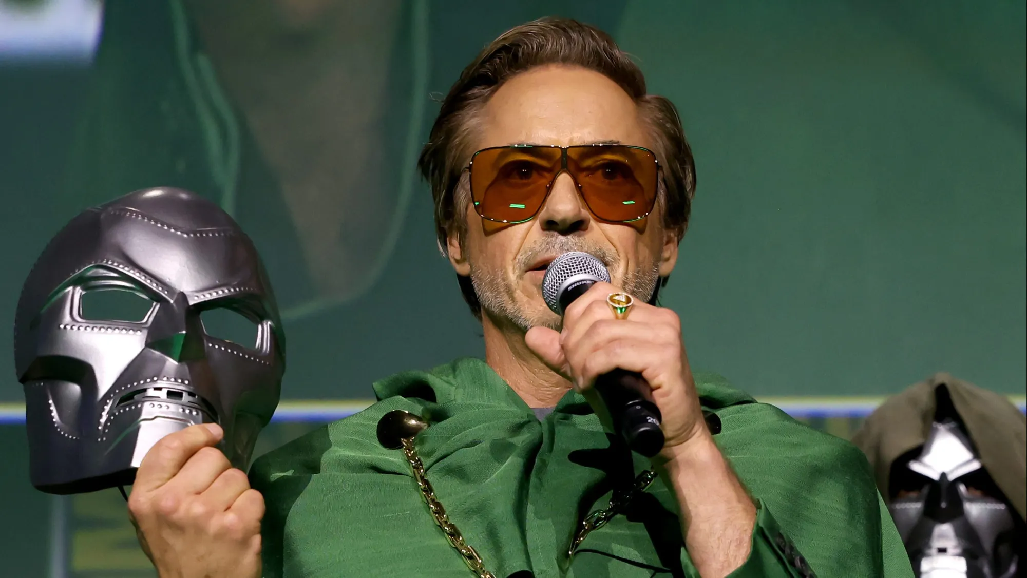 Robert Downey Jr. holding a Doctor Doom mask during a Marvel presentation