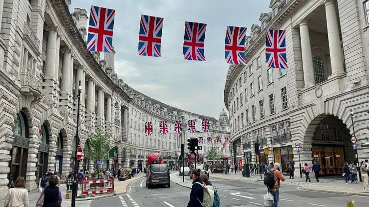 Tourists and pedestrians in central London beneath Union flags