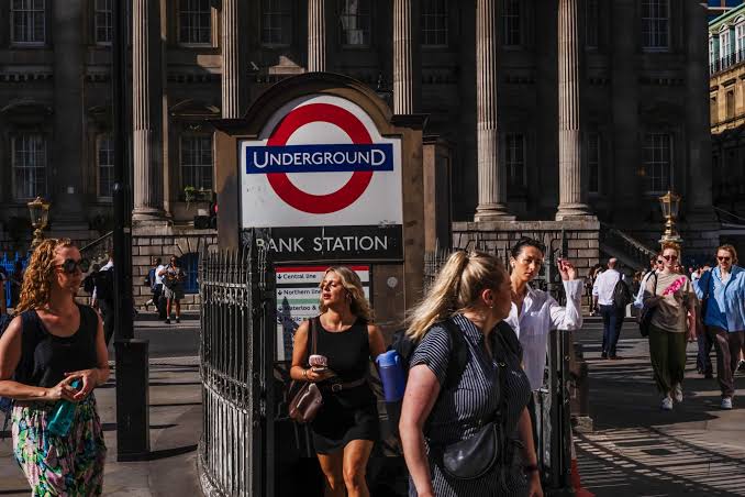 Commuters walking through London's business district as UK PAYE payroll data show rising employee outflows